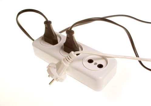 Three white and black electrical plugs into white outlet on the white