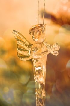 Glass angel decoration in christmas tree with colorful background