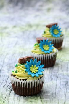 Three chocolate cupcakes decorated with icing and flowers