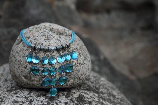 Blue gem necklace on a round grey rock