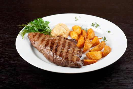 Juicy beef steak stuffed with beef tongue and cheese served with potatoes, greenery and sauce