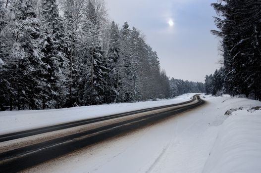 Winding country road in winter at sunset