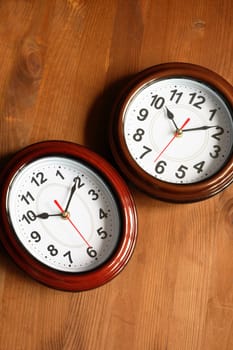 Pair of nice modern clocks on wooden surface