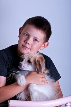 Young boy and dog. Portrait in studio on a grey background.