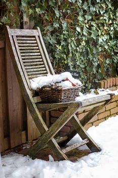 Gardenchair in winter with snow and  common Ivy growing in background
