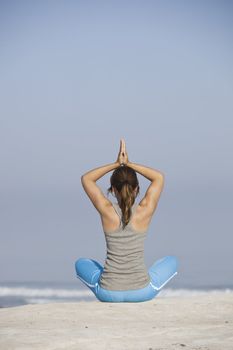 Beautiful young woman with arms open, relaxing on the beach