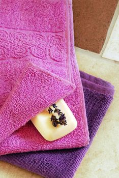 purple and magenta towels with white soap and dry lavender flowers