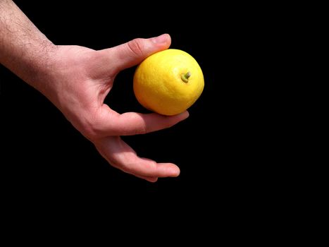 Men's hand holding a lemon. Black background.