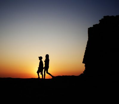 Two children walking around at sunset.