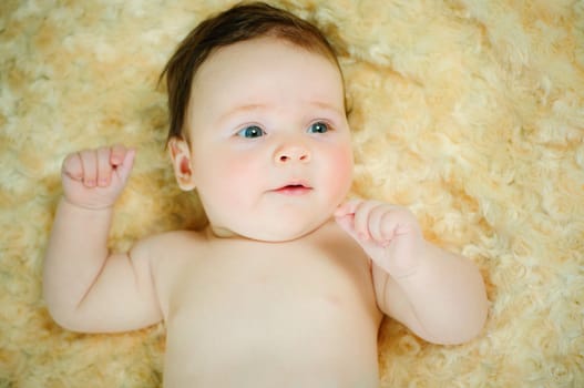 Beautiful cute baby boy is lying in a bed.