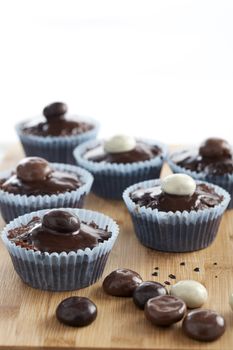 Chocolate cupcakes topped with chocolate sauce and chocolate covered candies.