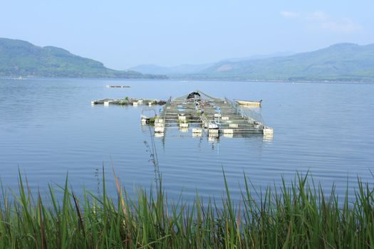 Scenery of a floating basket for keeping live fish in water at a dam of Thailand