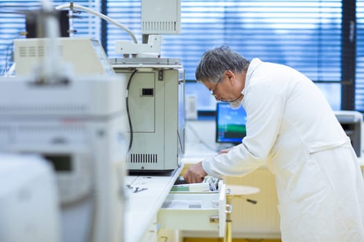 senior male researcher carrying out scientific research in a lab (shallow DOF; color toned image)