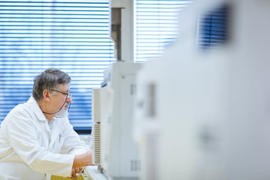 senior male researcher carrying out scientific research in a lab (shallow DOF; color toned image)