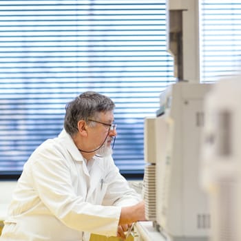 senior male researcher carrying out scientific research in a lab (shallow DOF; color toned image)