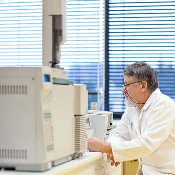 senior male researcher carrying out scientific research in a lab (shallow DOF; color toned image)