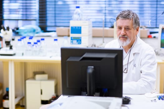 senior male researcher carrying out scientific research in a lab (shallow DOF; color toned image)