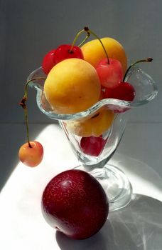 Cherry and apricot in glass vase with big plum ahead