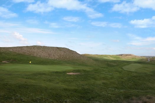 a flag waving on a hole on a golf course in ireland