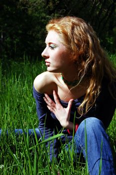 Red-haired girl in high green grass