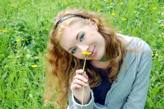 Lovely red-haired girl sniffing dandelion 