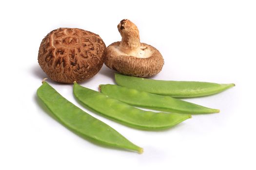 Fresh green peas and brown mushroom on white background.