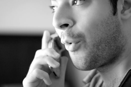 Black and white portrait of a young man on his cell phone - he looks surprised from what he has just heard.