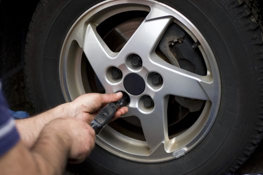 Close-up detail of a mechanic tightening or loosening the lugs of an aluminum rim.