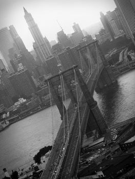 A black and white aerial shot of the famous Brooklyn Bridge and NYC skyline.