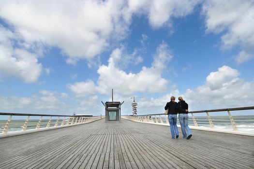 Two female friends walking on a pier