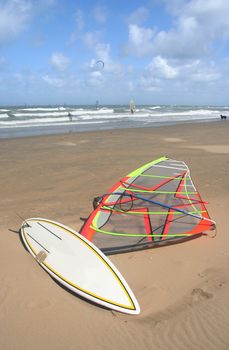 Surfboard and sail lying on the beach