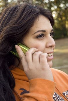 A beautiful young woman of latin descent talking on a cell phone.
