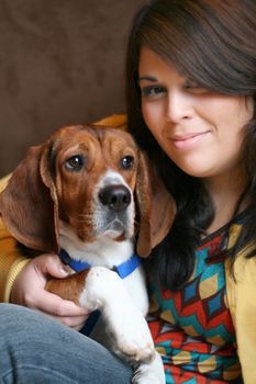 Portrait of a girl in her twenties posing with a young purebred beagle pup.