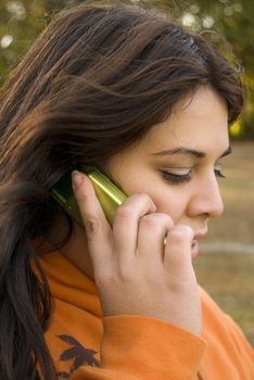 A beautiful young woman of latin descent talking on a cell phone