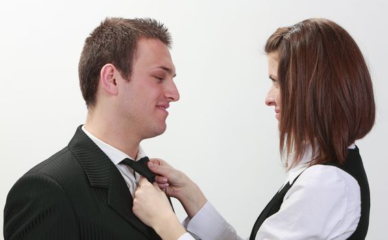 A businesswoman tying man's tie,isolated against a white background.