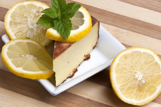 A piece of lemon cake decorated with lemon slices and mint leaves