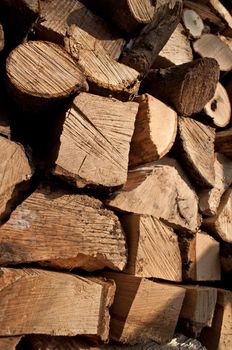 Close up on the ends of a large group of stacked, chopped rustic fire wood in outdoor setting with full sunlight
