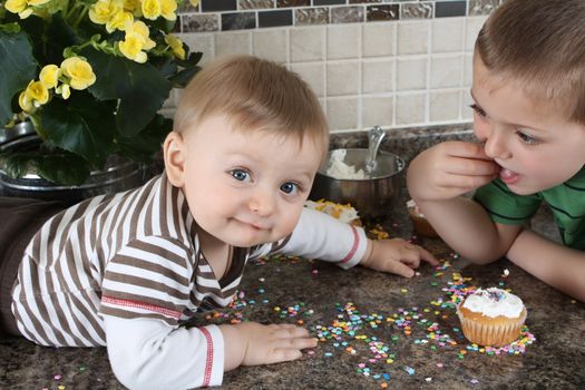 Brothers on kitchen counter eating icing sugar