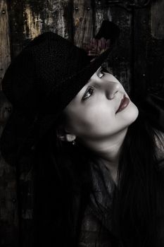 Brunette female with hat in front of antique trunk