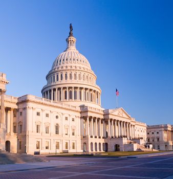 Capitol building in Washington DC illuminated early in the morning by the rising sun and giving a red/orange hue to the traditional scene