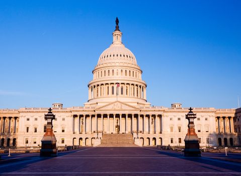 Capitol building in Washington DC illuminated early in the morning by the rising sun and giving a red/orange hue to the traditional scene