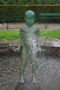 Statue of crying boy in fontain in city park of Bergen, Norway