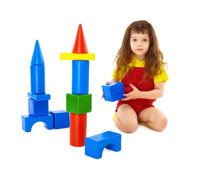 The child builds a toy castle on the floor isolated on white background