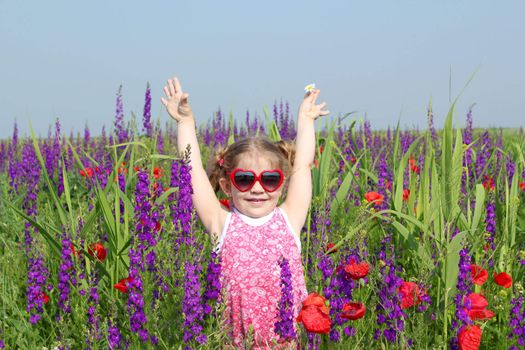 happy little girl standing in colorful meadow