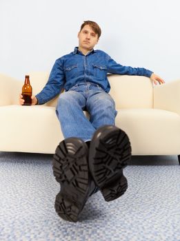 Drunk dude sprawled comfortably on the couch with beer