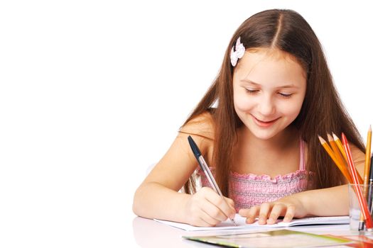 Cute little girl writing something in the copybook and smiling.