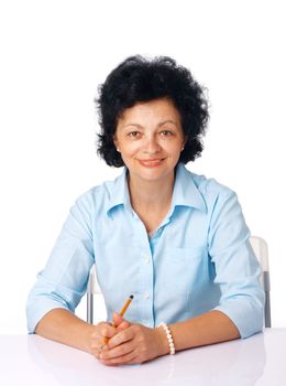 Elder woman sitting at the table with her hands together holding a pencil