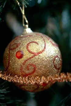  White Christmas ornament with ribbon hanging on a pine tree branch. 
