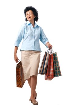 Happy elderly woman walking with shopping bags over white background.