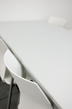 Detail of White Chairs and Table in Empty Meeting Room